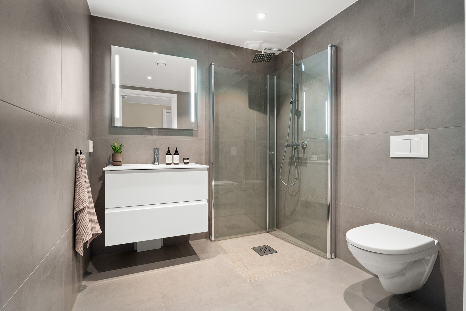 Her er det store, grå fliser på veggene, downlights i himlingen og lyse fliser på gulv med gulvvarme. Galleribilde