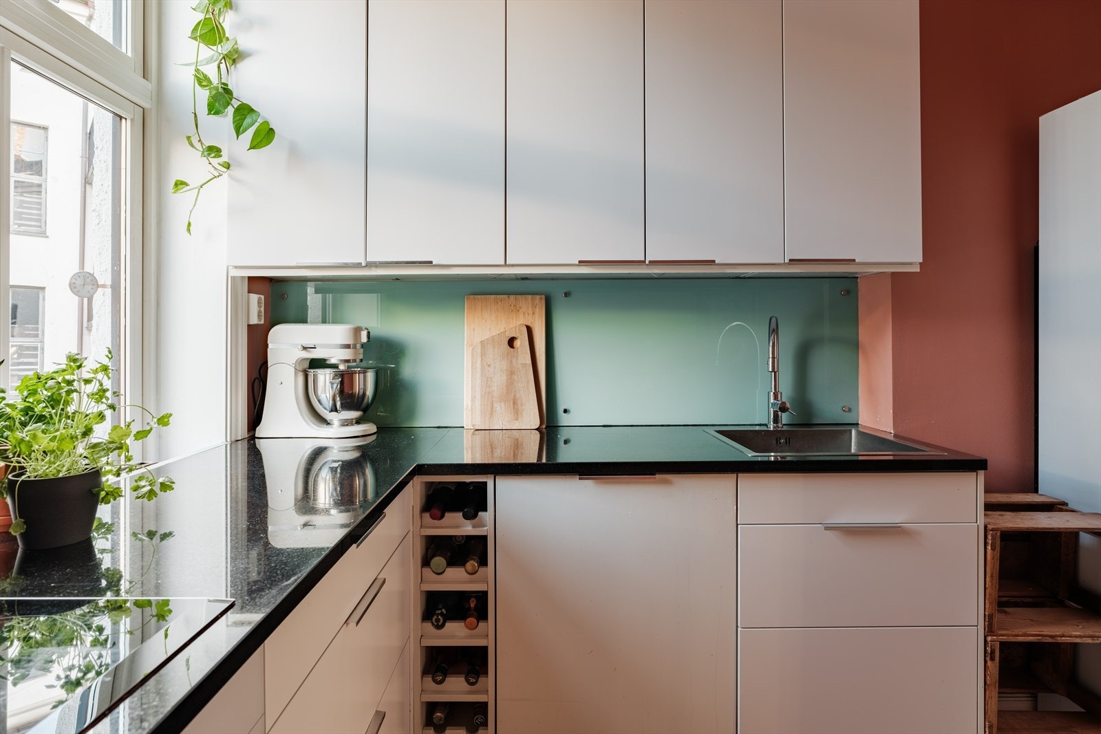 Kjøkkeninnredning med stein benkeplate med nedfelt oppvaskkum med 1-greps blandebatteri. Skylleplate mellom over og underskap. Det er montert en integrert oppvaskmaskin, integrert komfyr og nedfelt platetopp. Galleribilde