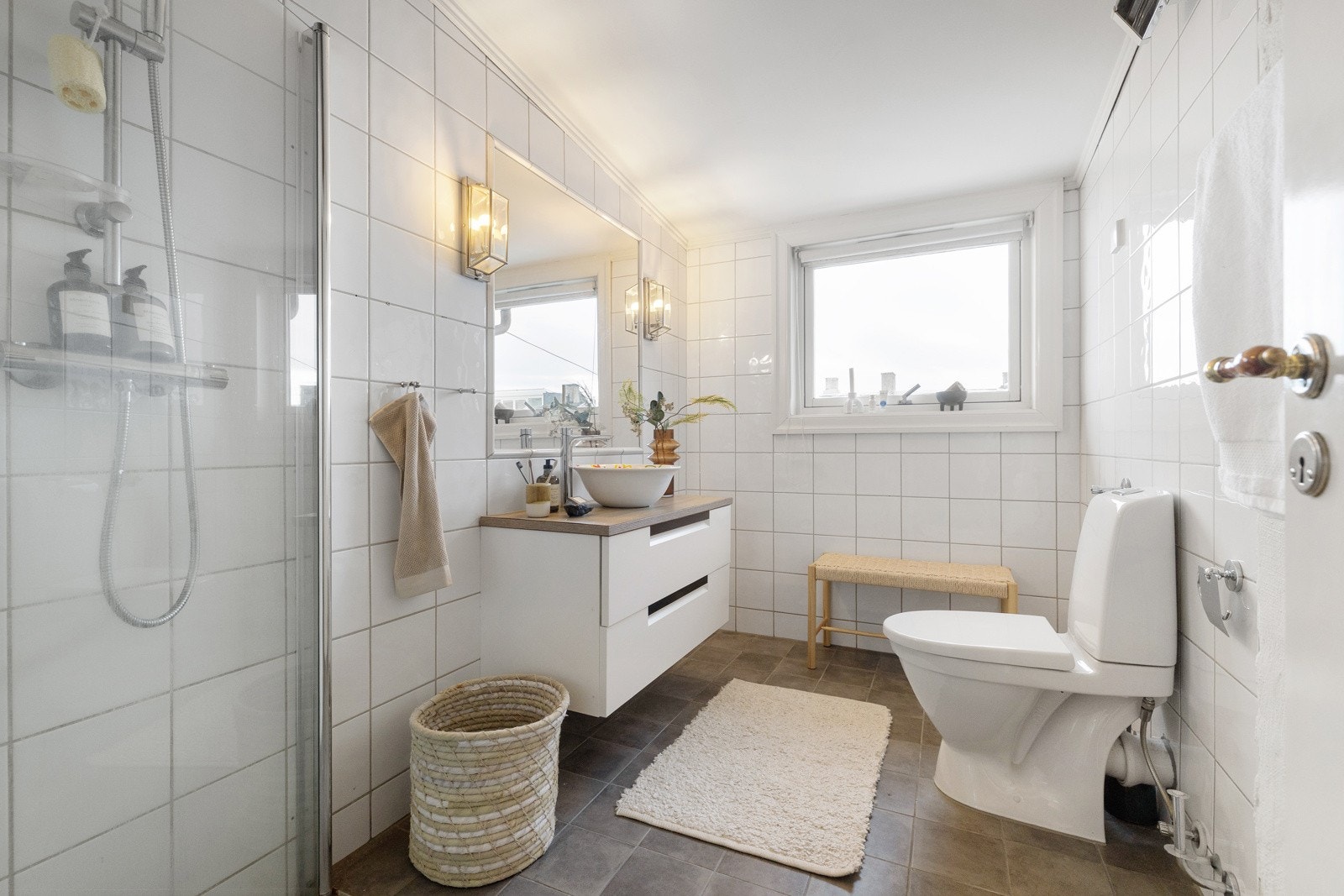 Flislagt bad innredet med innfellbare dusjdører, toalett og servantskap. Galleribilde