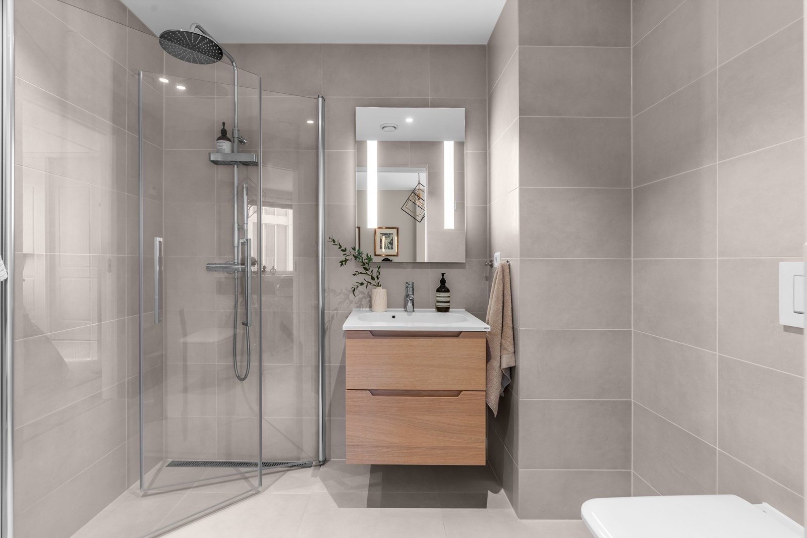 Delikat og innbydende bad 2 fra gangen med stor dusjsone, servant med underskap og vegghengt klosett Galleribilde