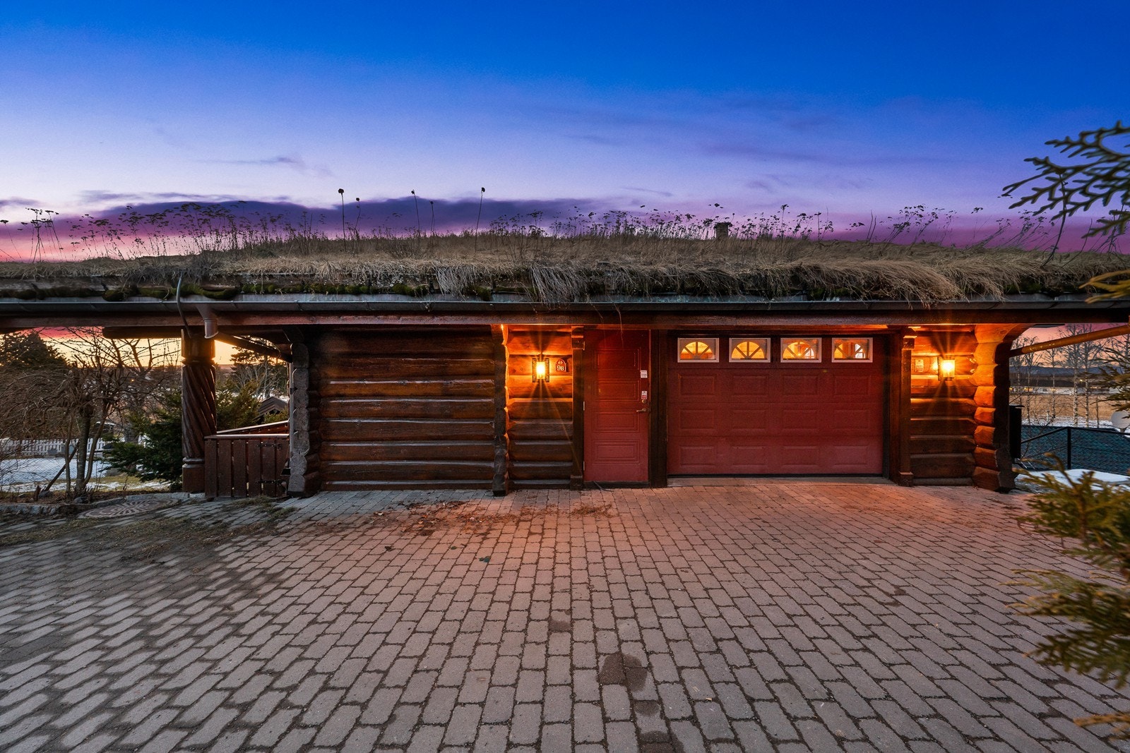 Steinlagt gårdsplass og garasje, direkte tilgang til boligen. Hovedinngangen til boligen er til høyre fra garasjen. Bilde er tatt i høst. Galleribilde