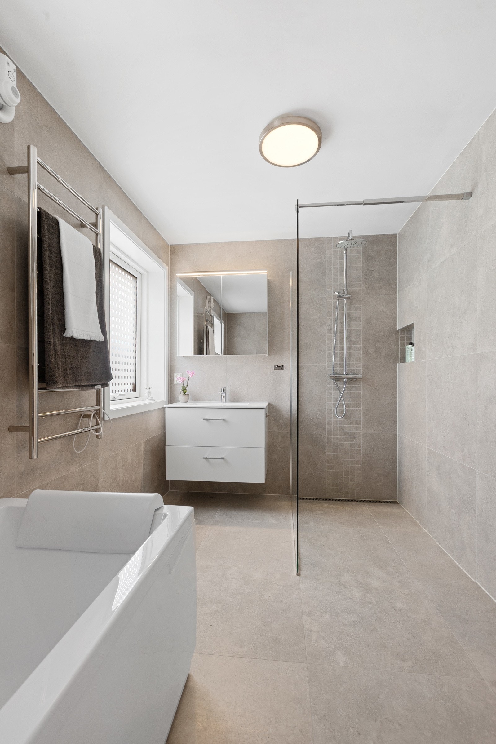 Badet har fliser på gulv og vegg - badekar og dusjhjørne - baderomsinnredning og toalett Galleribilde