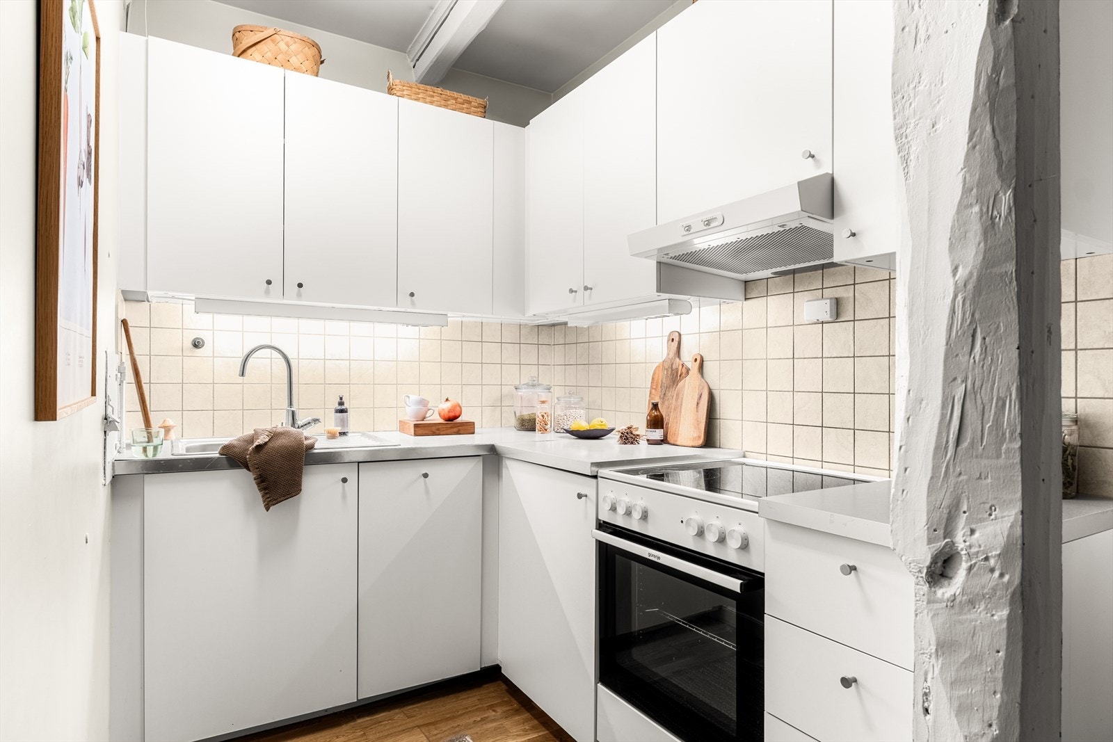 Her er det enkel kjøkkeninnredning med slette fronter, belysning og fliser over laminat benkeplate med oppvaskkum og blandebatteri. Det er montert frittstående komfyr, kjøl/frys og integrert oppvaskmaskin. Galleribilde