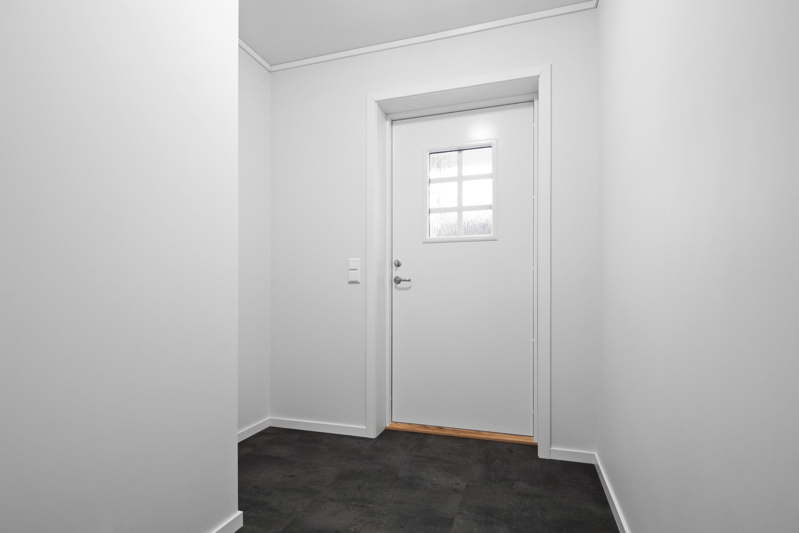 Vel inne er entreen innredet med hvitmalte vegger og flismønstert laminatgulv Galleribilde