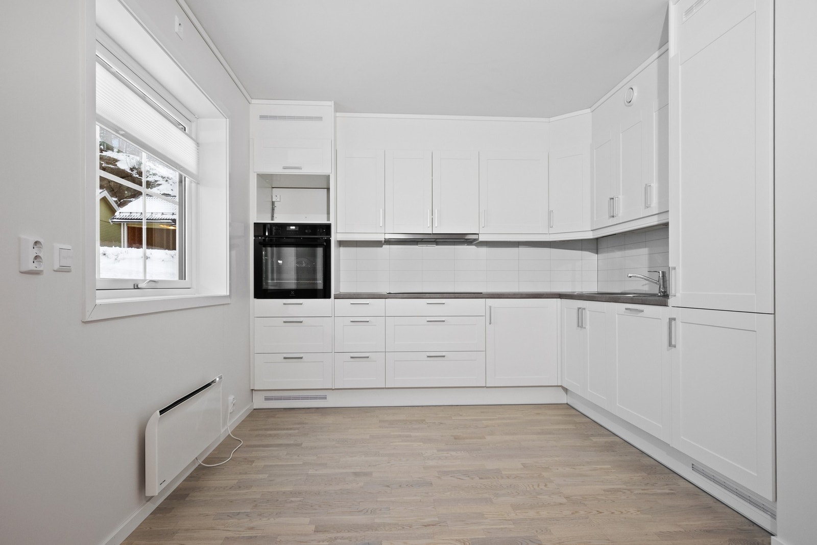 Innredningen har hvite, profilerte fronter, nedfelt oppvaskkum og benkeplate av laminat Galleribilde