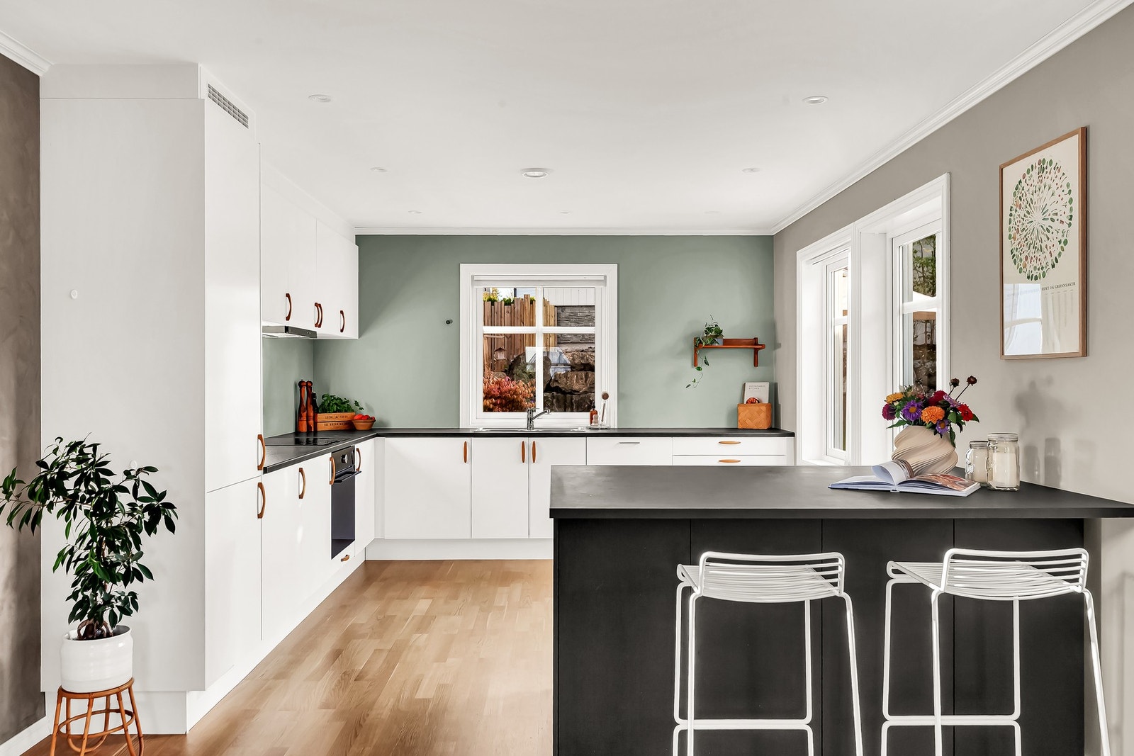 Kjøkkenet er i en delikat utførelse med hvite fronter og mørk benkeplate som harmonerer pent med den grønne veggen Galleribilde