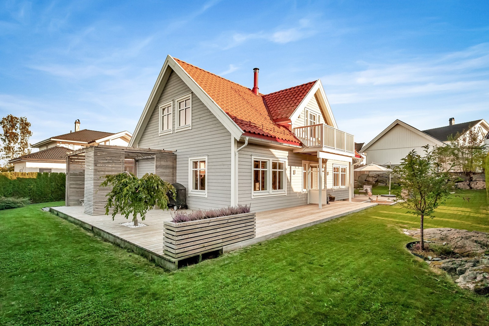 Boligens uteområde er pent opparbeidet med plen, hekk og prydbusker samt noe fjell i dagen Galleribilde