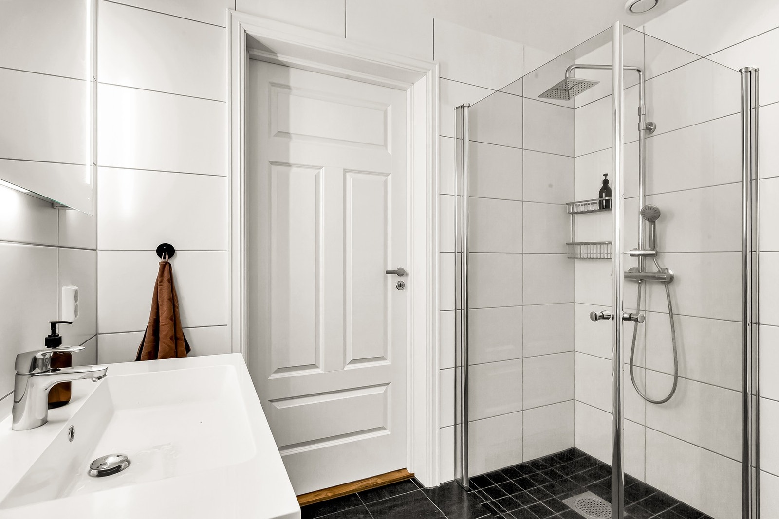 Badet er innredet med servant i skuffeinnredning med speil og lys over. Galleribilde