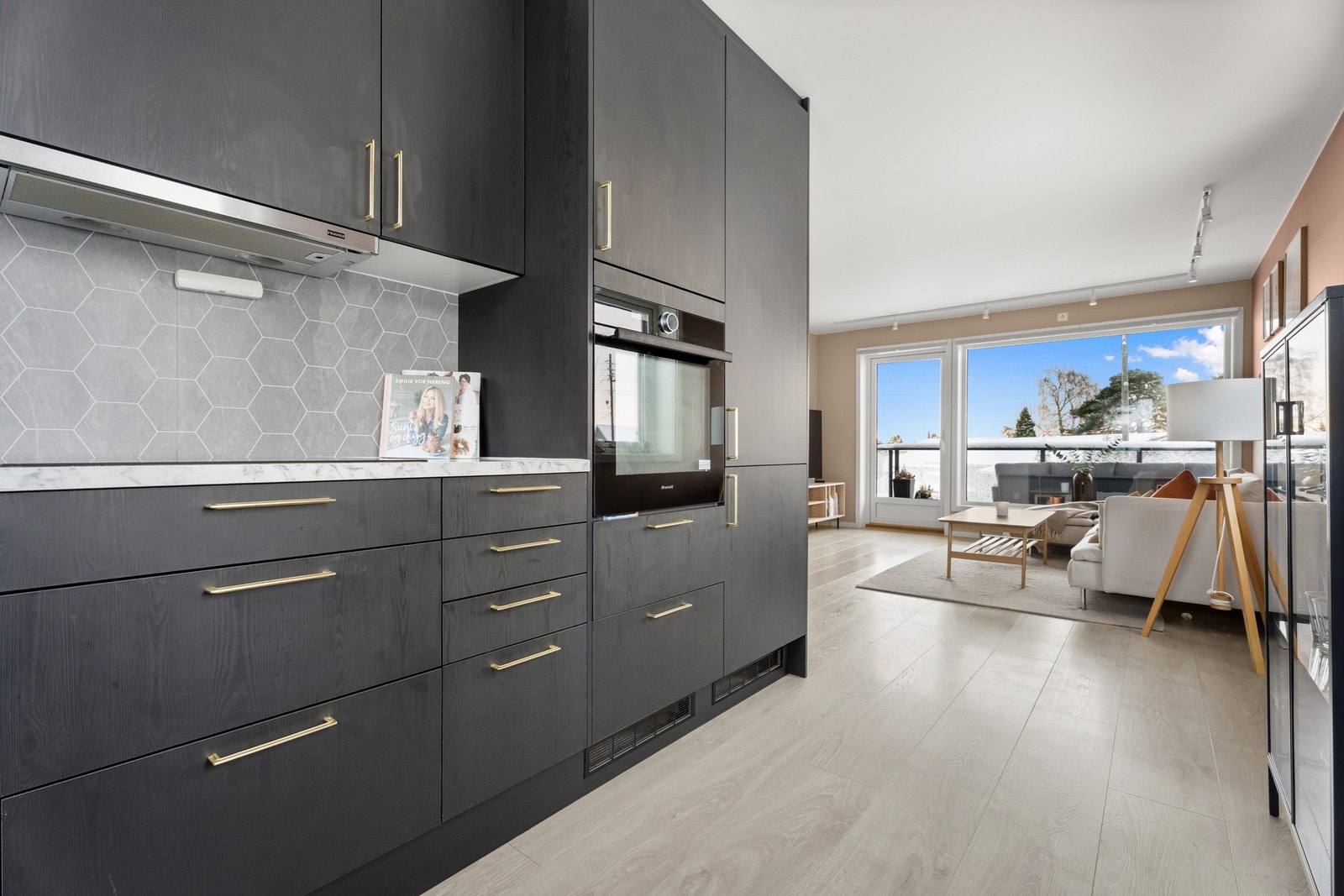 Kjøkkenet med sorte fronter og gullfargede håndtak som gir et eksklusivt preg. Galleribilde