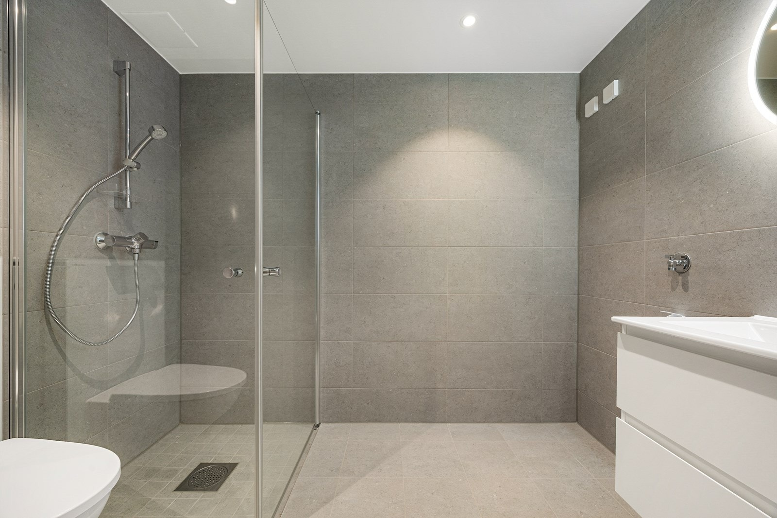 Badet på 4,2 m² er flislagt med store, moderne fliser og har varmekabler i gulvet. Galleribilde