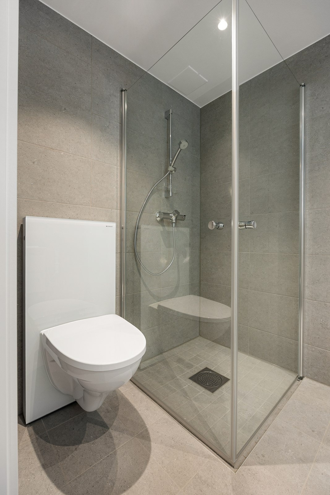 Rommet er utstyrt med vegghengt toalett og et dusjhjørne med innfellbare glassdører. Galleribilde