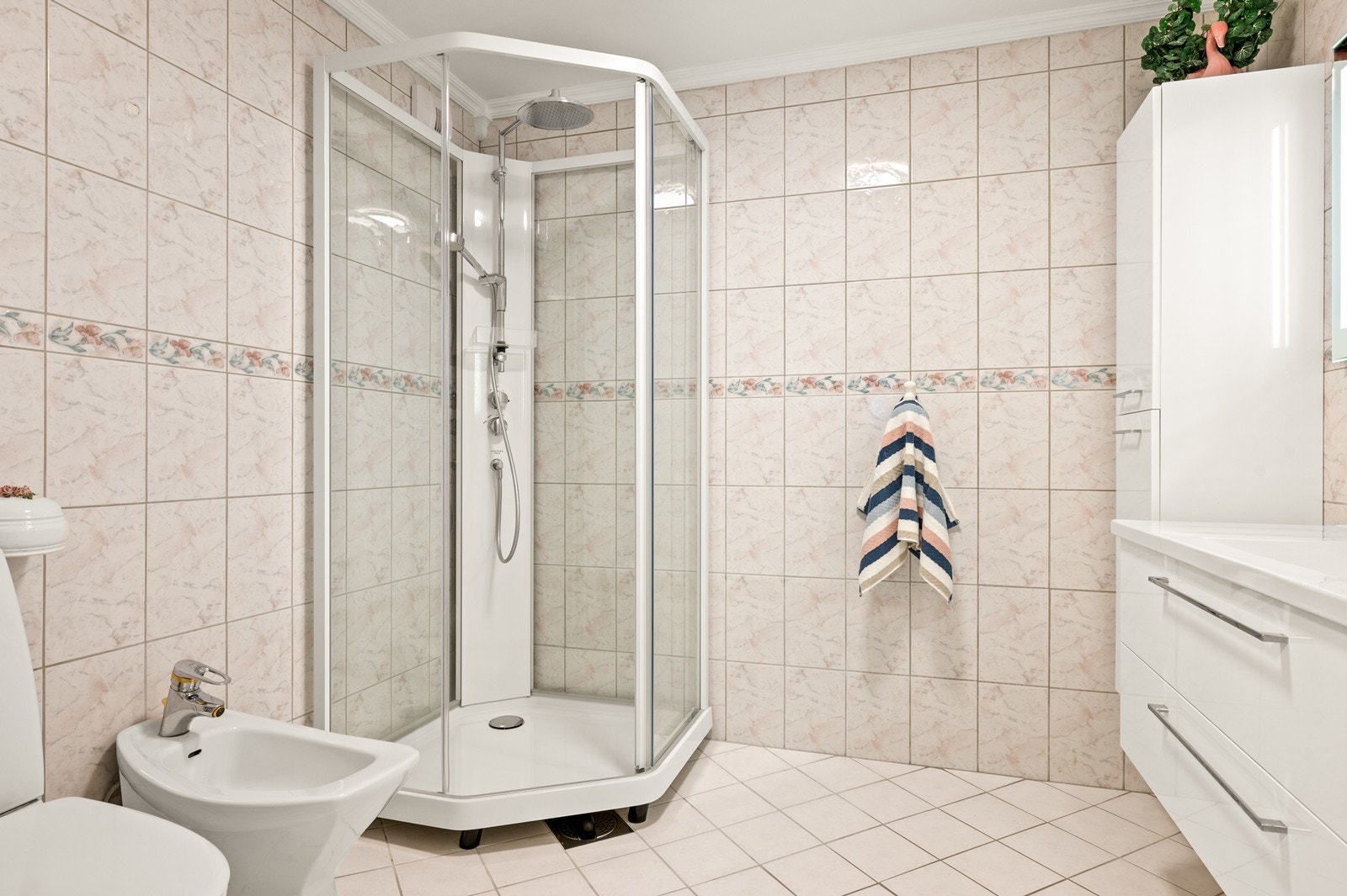 Badet er helfliset og utstyrt med dusjkabinett, toalett og bidé. Galleribilde