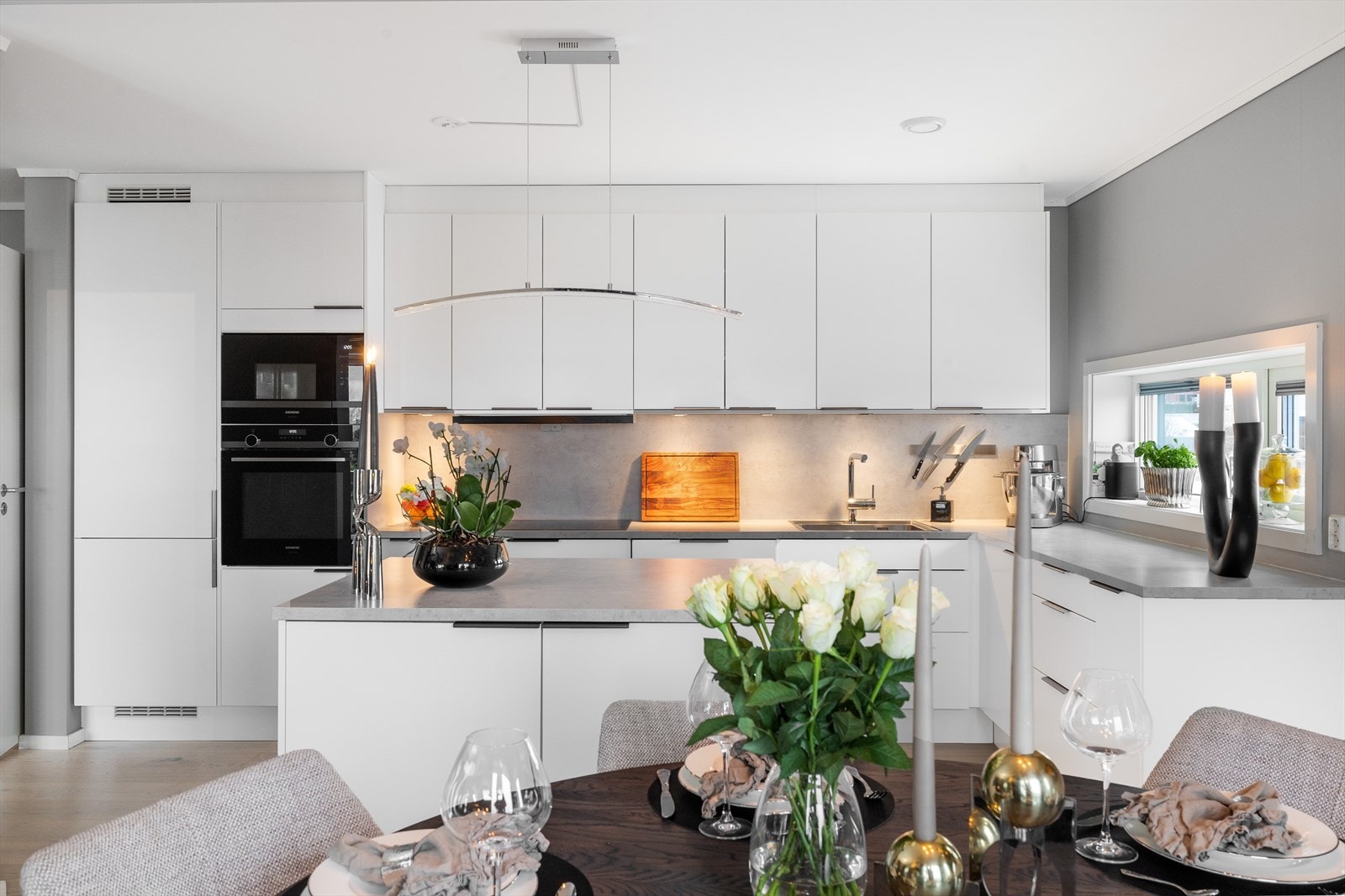 Kjøkkenet er fra byggeåret og fremstår som moderne og funksjonelt med slette, malte fronter og en praktisk kjøkkenøy som fungerer som et naturlig samlingspunkt. Det er rikelig med skap- og benkeplass, og alle hvitevarer er integrerte. Galleribilde