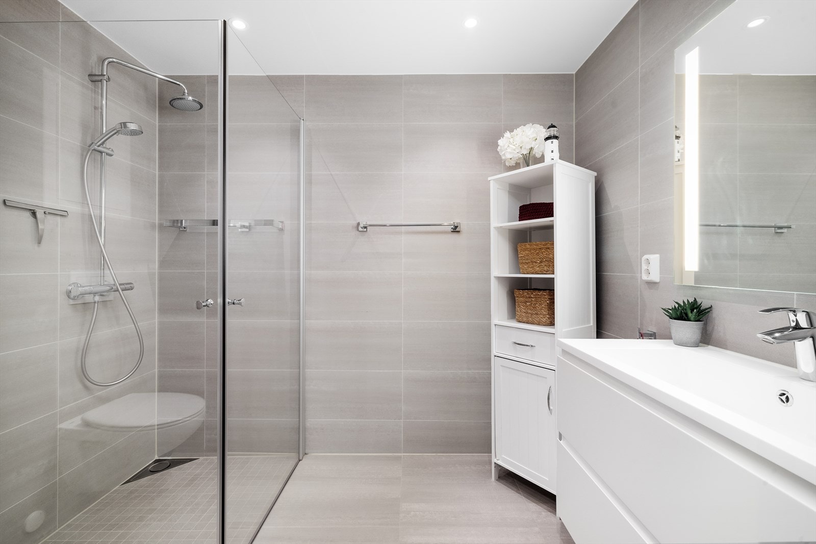 Fra garderoben er det videre inngang til et privat, flislagt bad utstyrt med moderne baderomsinnredning, vegghengt toalett og dusjsone. Galleribilde