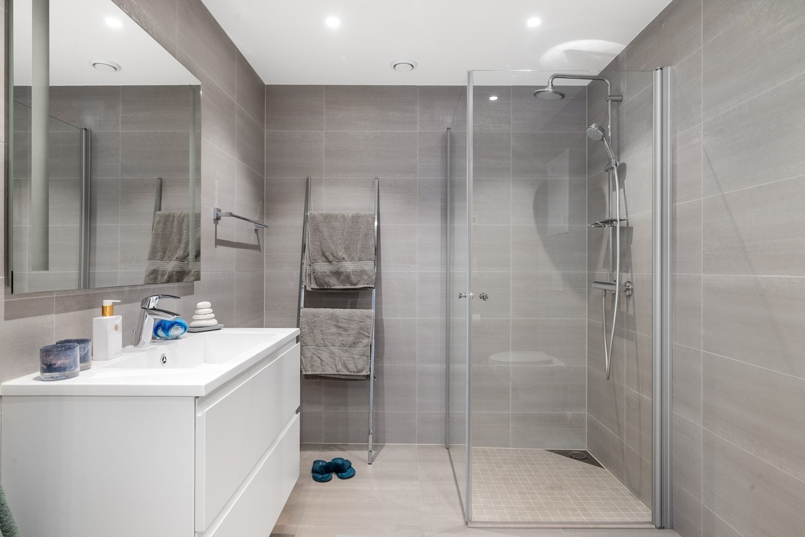 Badet i denne etasjen holder samme høye kvalitet som i overetasjen, med fliser på gulv og vegger, varmekabler, moderne servantinnredning og dusjhjørne. Galleribilde