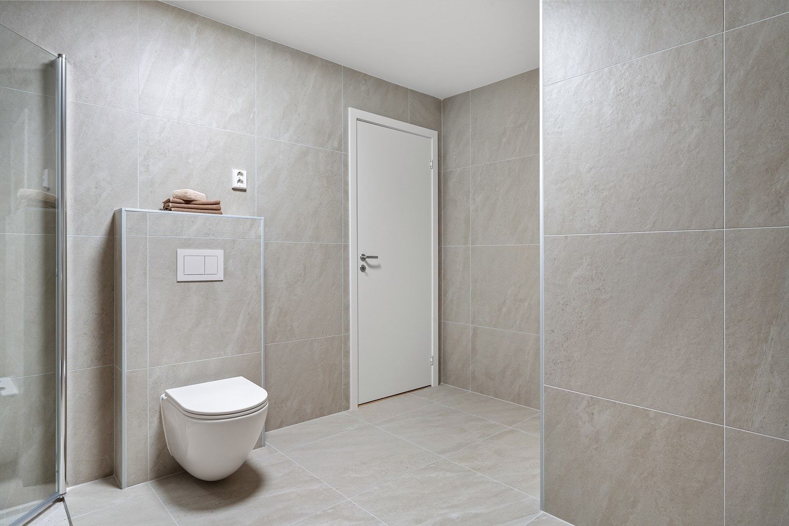 Moderne bad med elegant design, flislagte vegger og gulv, og vegghengt toalett. Galleribilde