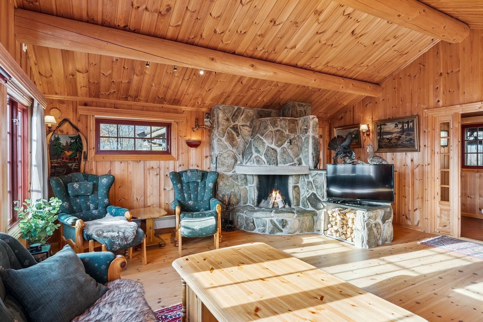 Stua er lys og innbydende, og den gode takhøyden med synlige tømmeråser skaper en luftig romfølelse. Galleribilde