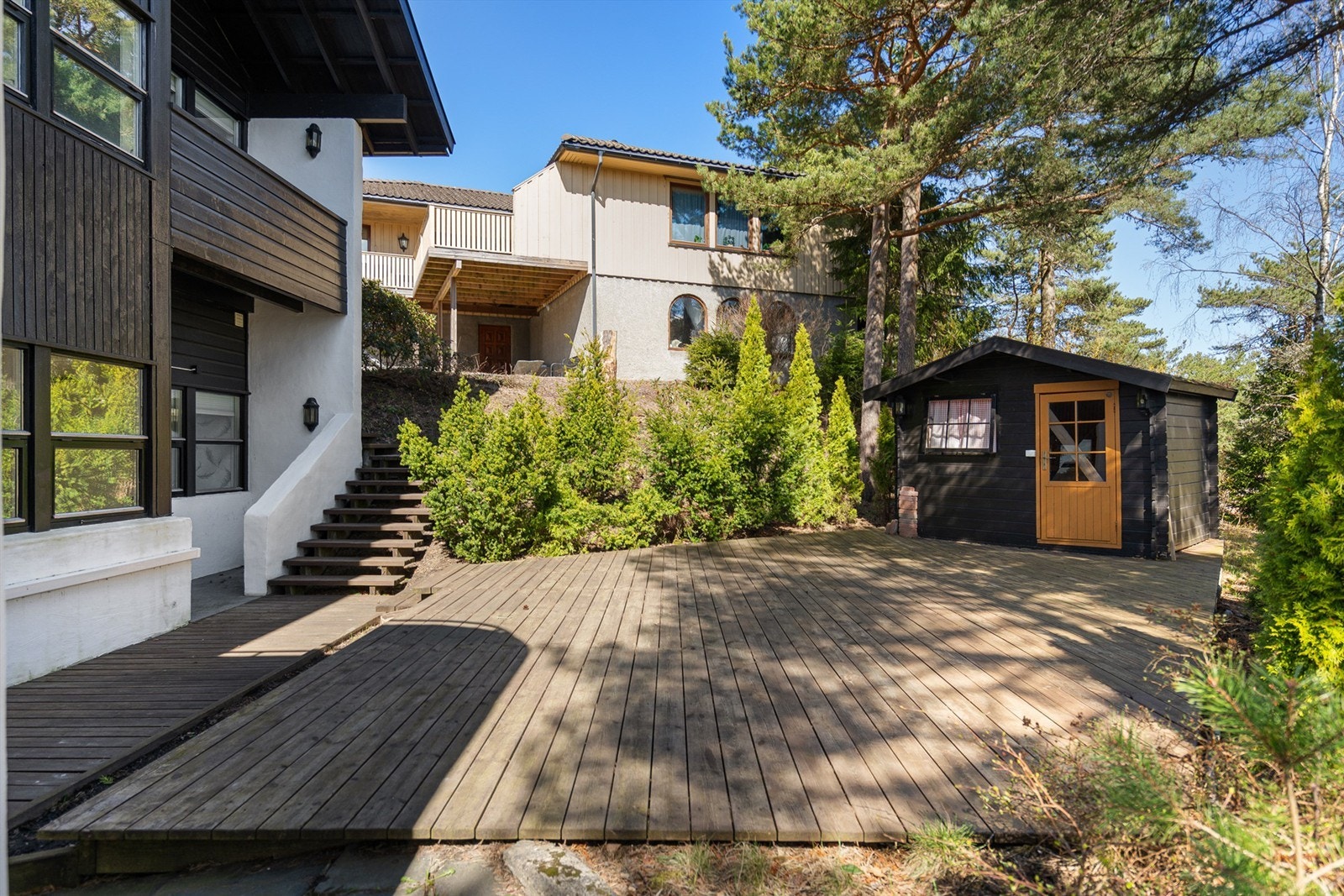 På den bakre østsiden finnes en mer tilbaketrukken terrasse, med bod/lekestue. Galleribilde