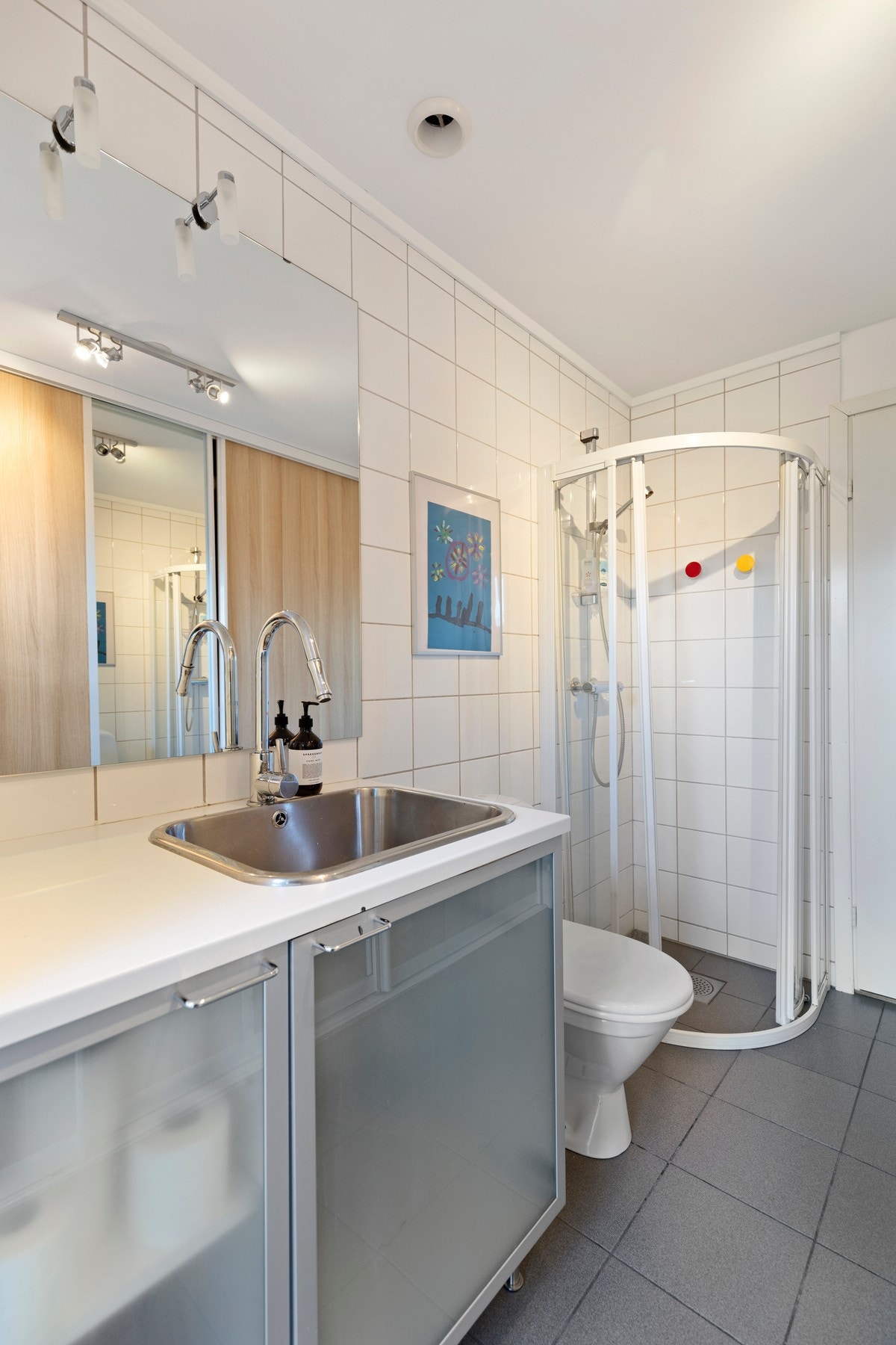 Rommet er utstyrt med dusjhjørne, toalett, opplegg for vaskemaskin/tørketrommel, samt innredning med skyllekum og tilhørende speil. Galleribilde