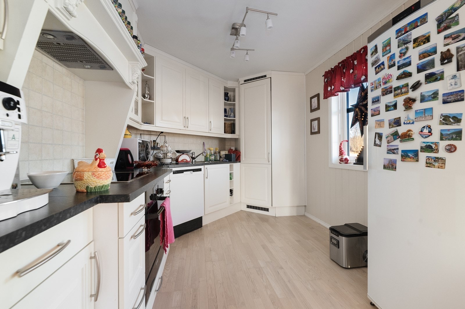 Kjøkkeninnredningen har over- og underskap med profilerte fronter, hyller og vitrineskap. Benkeplaten er laminert med nedfelt vask. Galleribilde