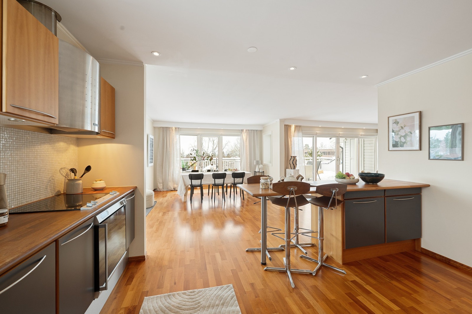 Stort og lyst oppholdsrom i L-form med stue, spisestue og kjøkken. Kjøkkenet er fint skjermet fra stuesonen. Galleribilde