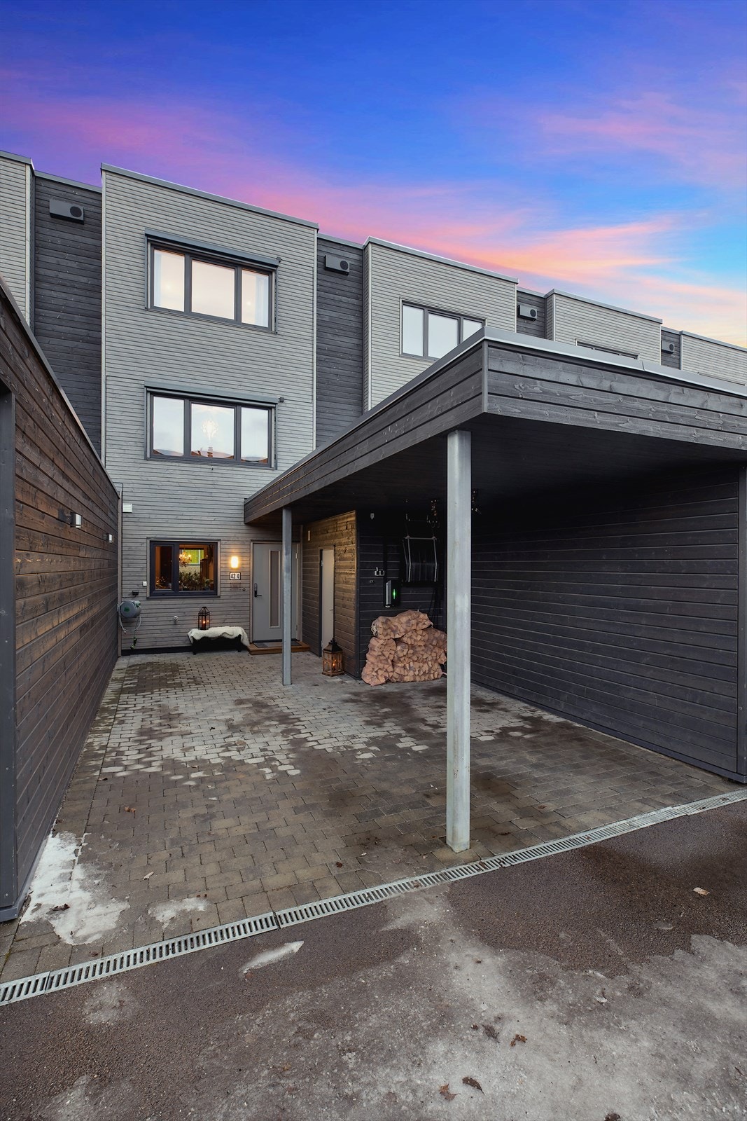 Steinlagt inngangsparti med carport med elbil-lader type 2 som leverer fra seg 11 kwh. Praktisk sportsbod rett utenfør inngangsdøren Galleribilde