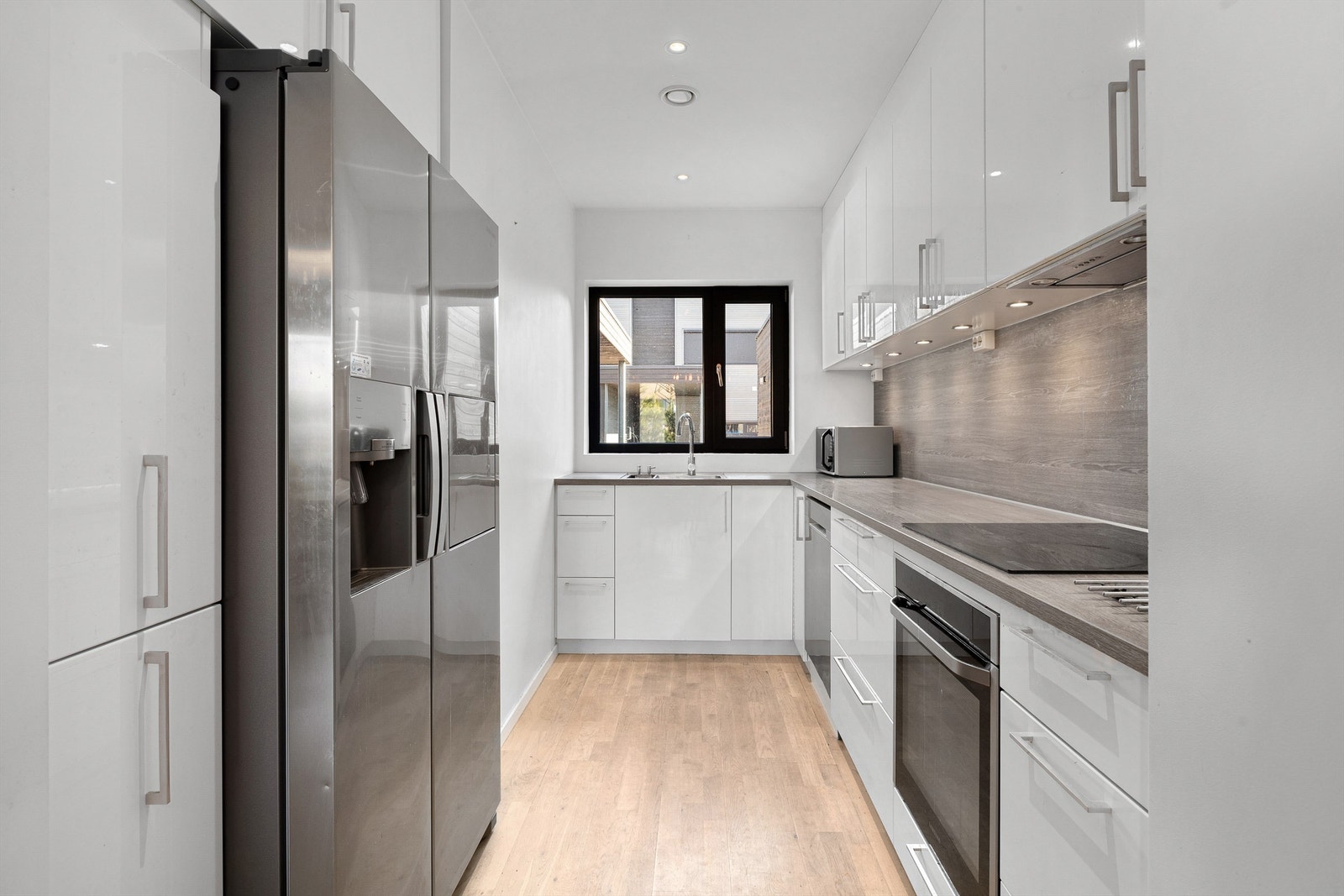 Lyst og pent kjøkken med over- og underskap i lyse slette fronter. Godt med skap- og benkeplass Galleribilde