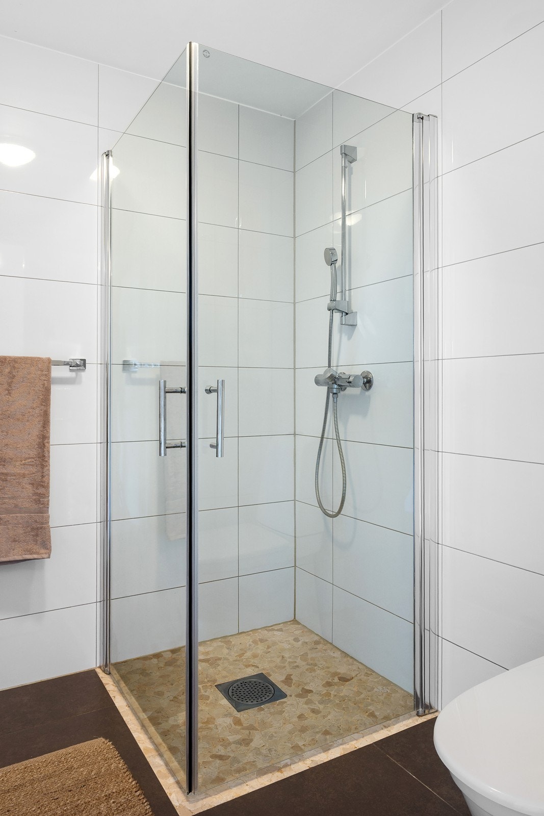 Dusjhjørnet har mosaikk naturstein på gulv og glassdører. Galleribilde