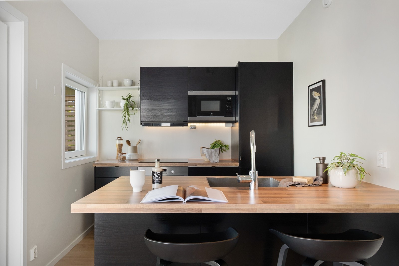 Kjøkkeninnredningen fra Epoq har sorte slette fronter og en lys laminat benkeplate. Integrerte hvitevarer består av platetopp, stekeovn, mikro, oppvaskmaskin og kjøl-/fryseskap. Galleribilde