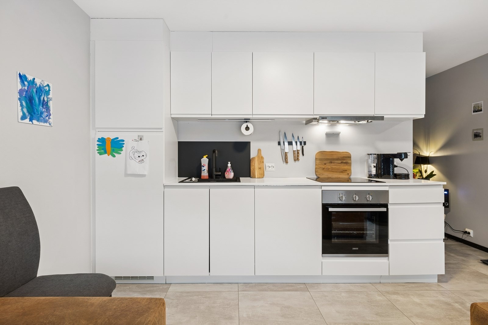 Praktikantdel: I stuen er det en moderne kjøkkeninnredning med slette hvite fronter, laminert benkeplate og integrerte hvitevarer, som stekeovn, platetopp og oppvaskmaskin. Galleribilde