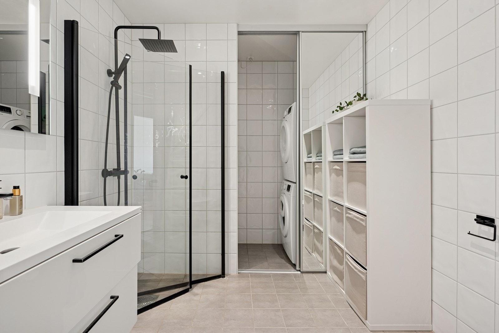 Innredningen består av en servantseksjon med nedfelt servant, veggmontert toalett, dusjhjørne med glassdører og opplegg for vaskemaskin og trommel bak skyvedører i glass. Galleribilde