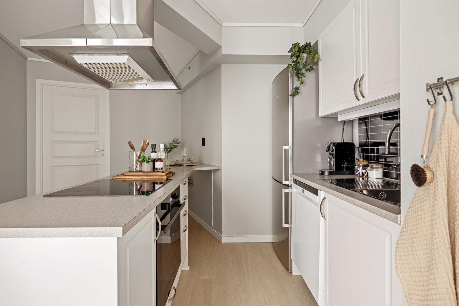 Kjøkkeninnredningen har profilerte fronter, kombinert med en laminert benkeplate og vask i stål for slitestyrke og funksjonalitet. Galleribilde