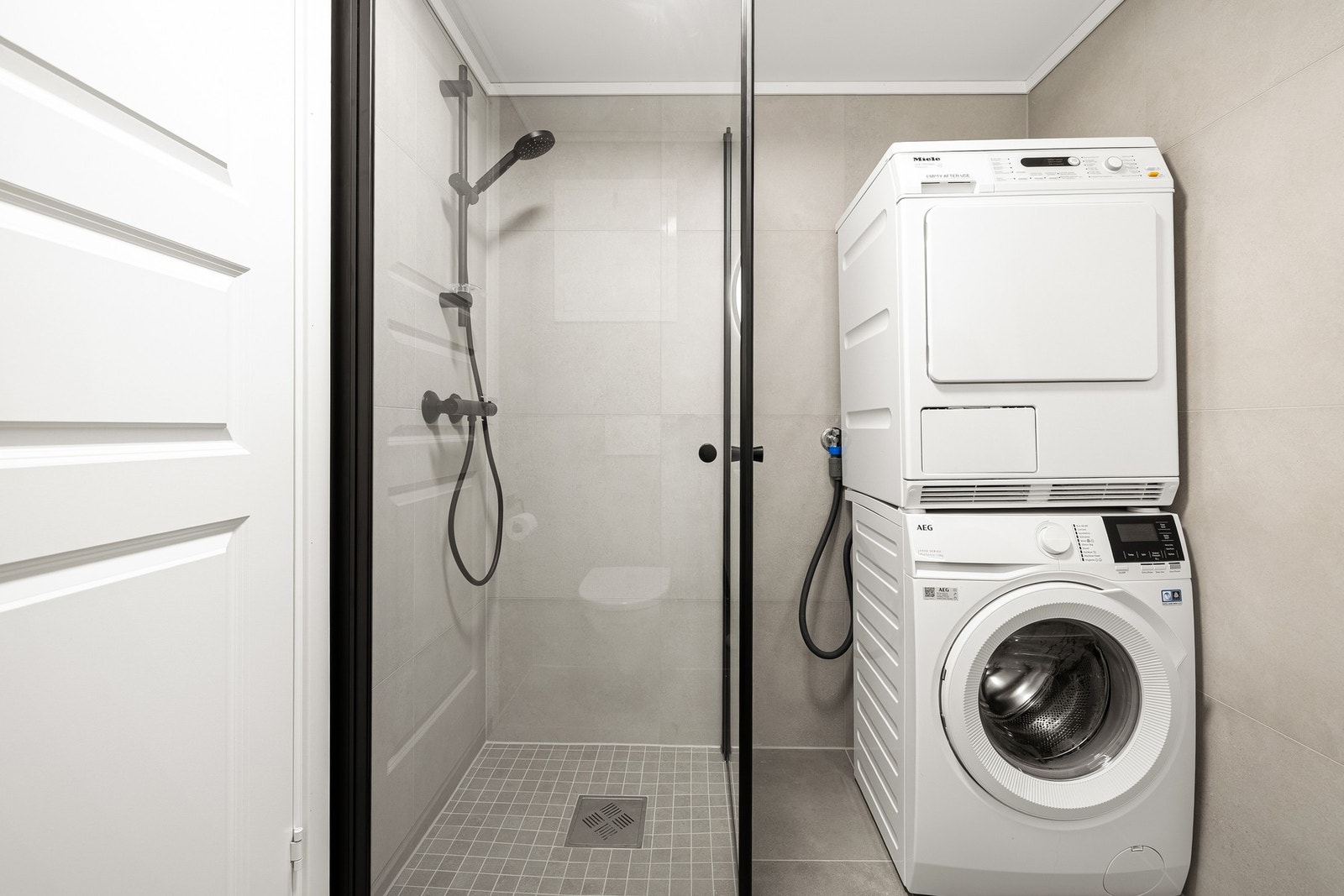 Badet er utstyrt med dusjhjørne med innfellbare glassdører, veggmontert toalett og servant med underskap for praktisk oppbevaring. Galleribilde