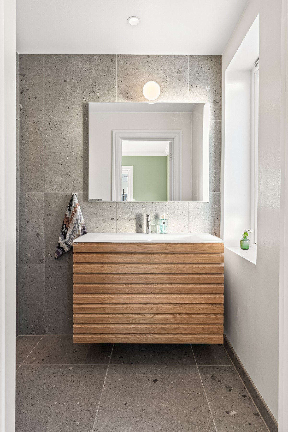 Baderomsinnredningen har profilerte fronter og heldekkende servant av glass. Galleribilde