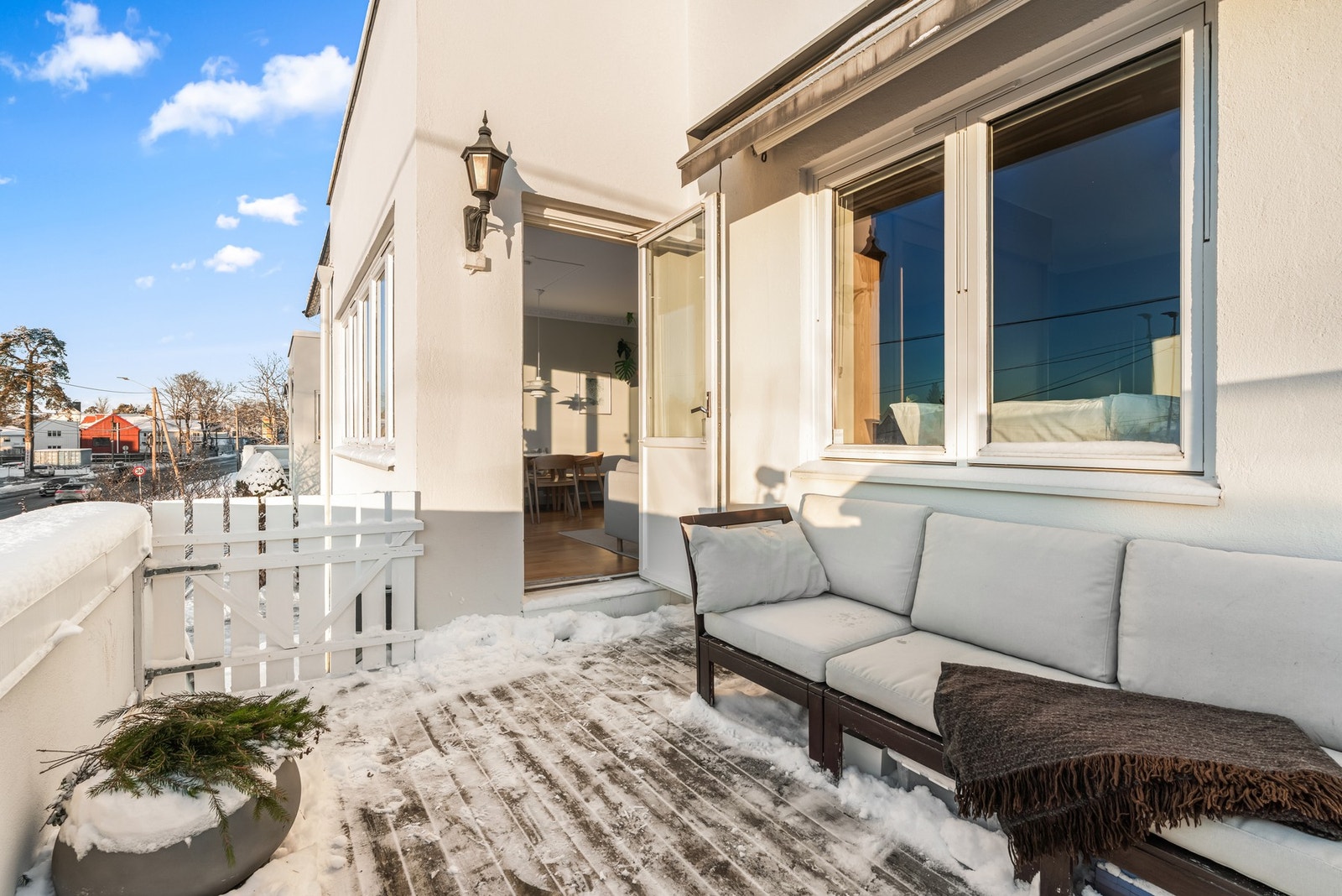 Terrassen har terrassebord i tre på støpt dekke og rekkverk av malt og pusset betong. På husveggen er det montert både utestikk og elektrisk markise. Galleribilde