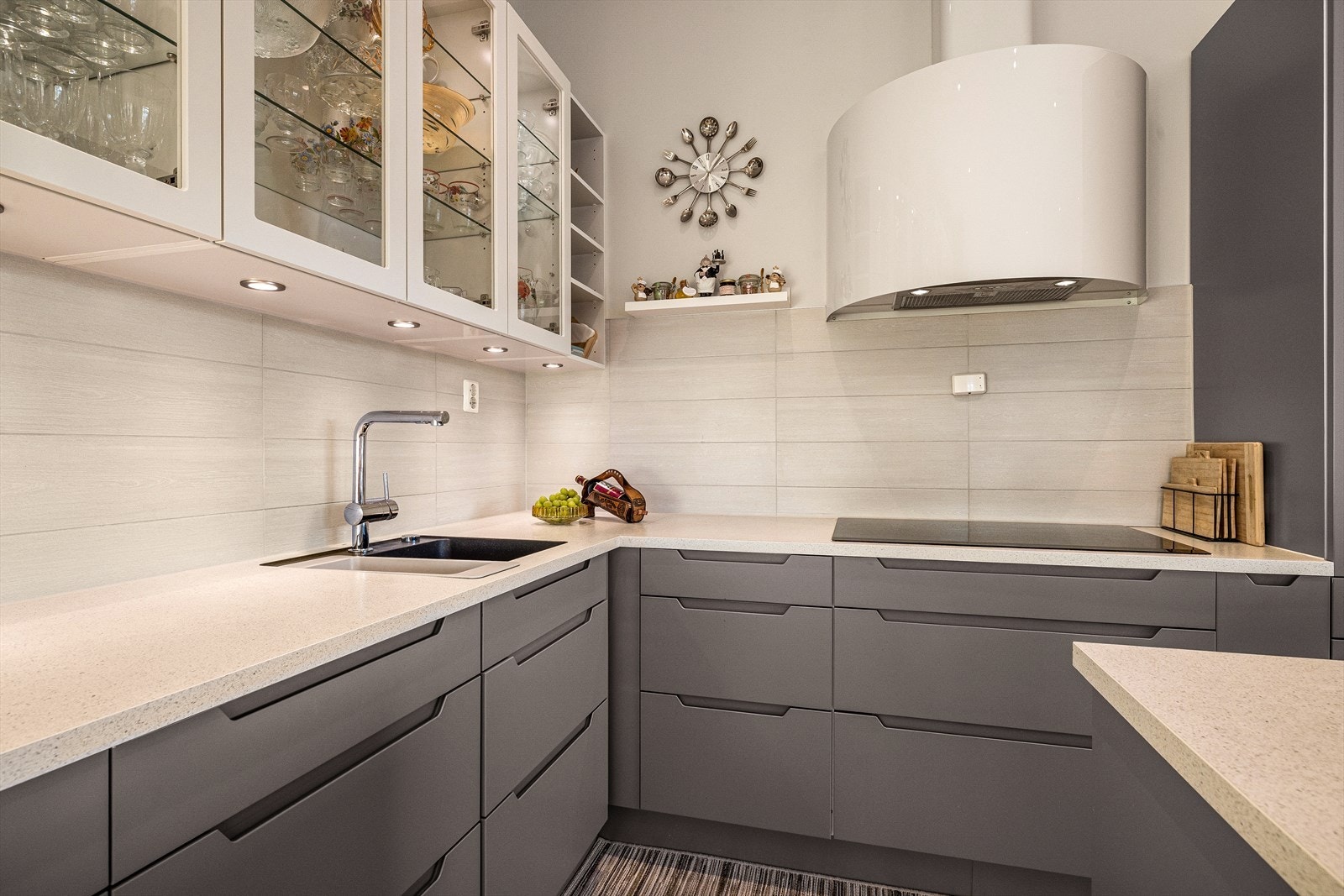 Det er laminat benkeplate og fliser på vegg mellom benkeplate og overskap. Galleribilde