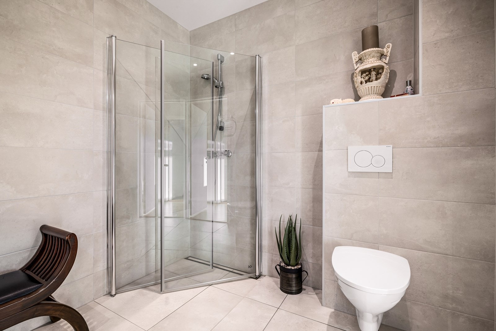 Videre er badet innredet med vegghengt toalett og dusjhjørne. Galleribilde