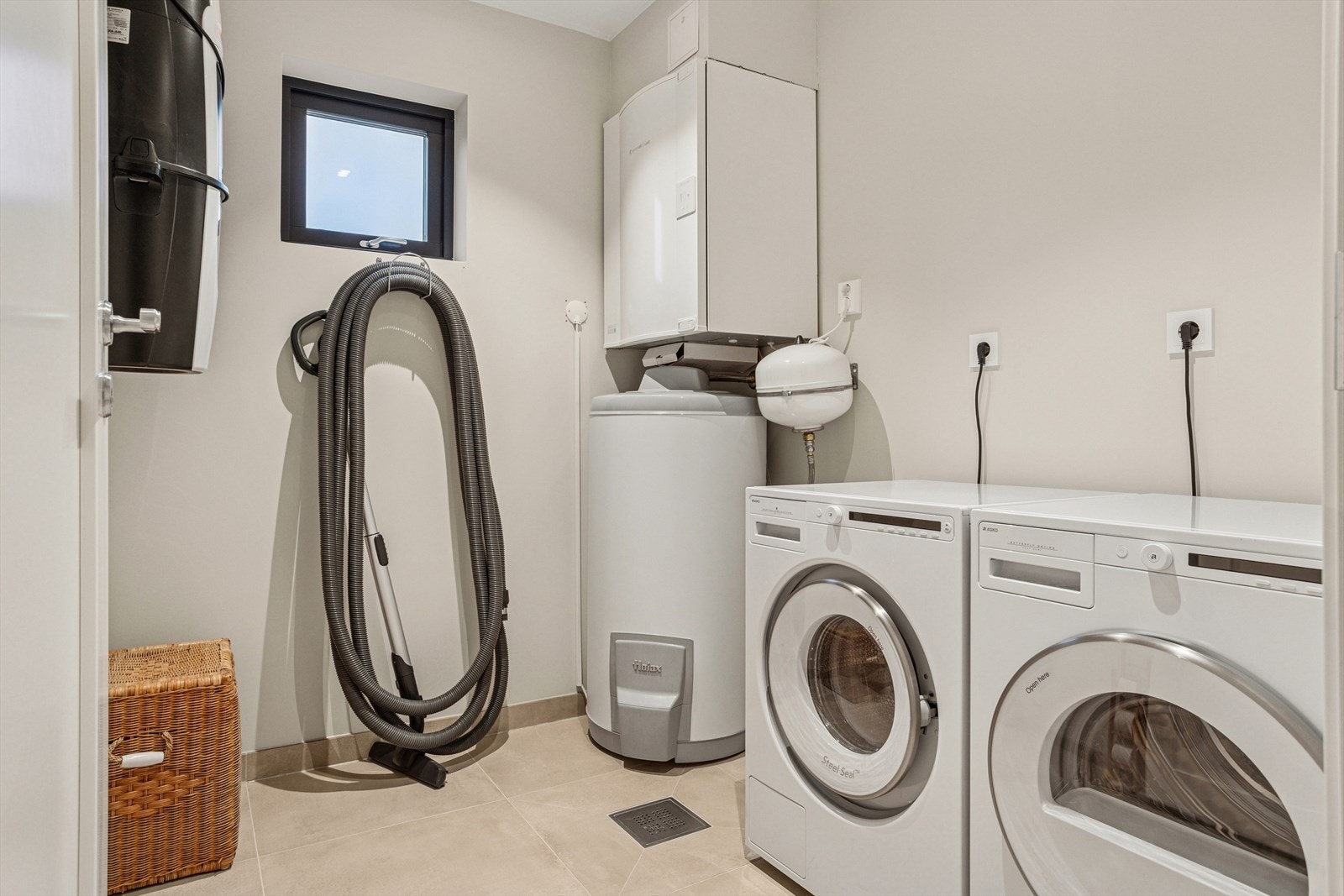 Separat vaskerom med flislagt gulv og plass til både vaskemaskin og tørketrommel Galleribilde
