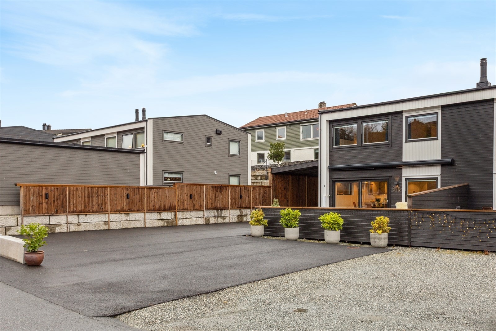 Tomten er pent opparbeidet med terrasser, murer, gjerde og stor asfaltert parkeringsplass Galleribilde