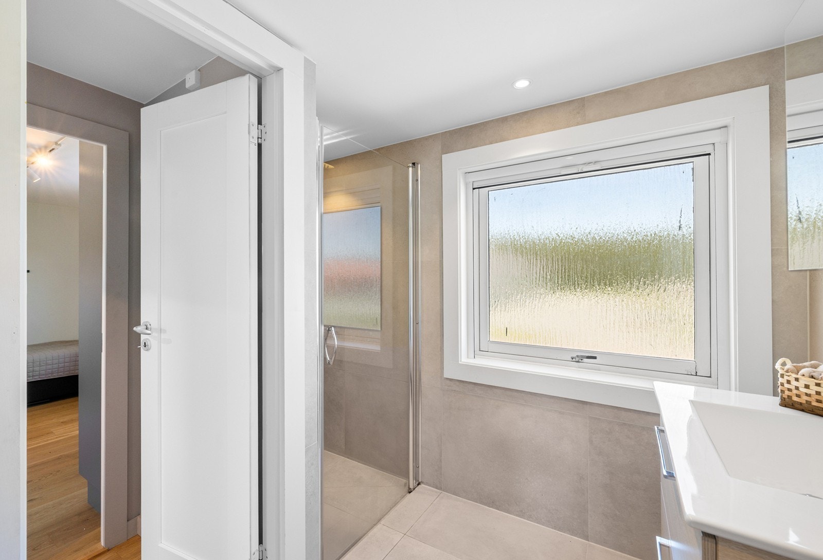 Dusjsonen er romslig og har glassvegg som skaper en åpen og luftig følelse. Et stort vindu slipper inn rikelig med naturlig lys samtidig som det frostede glasset ivaretar privatlivet. Galleribilde