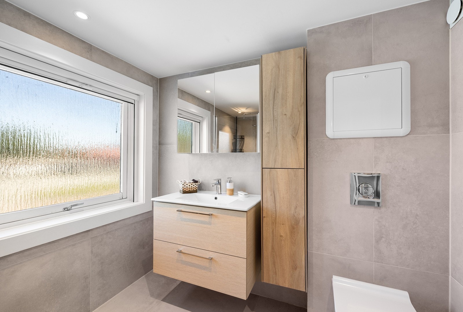 Badet fremstår som lyst og moderne med fliser i nøytrale fargetoner som gir en tidløs og stil. Rommet er utstyrt med gulvvarme som sørger for en behagelig temperatur hele året. Galleribilde