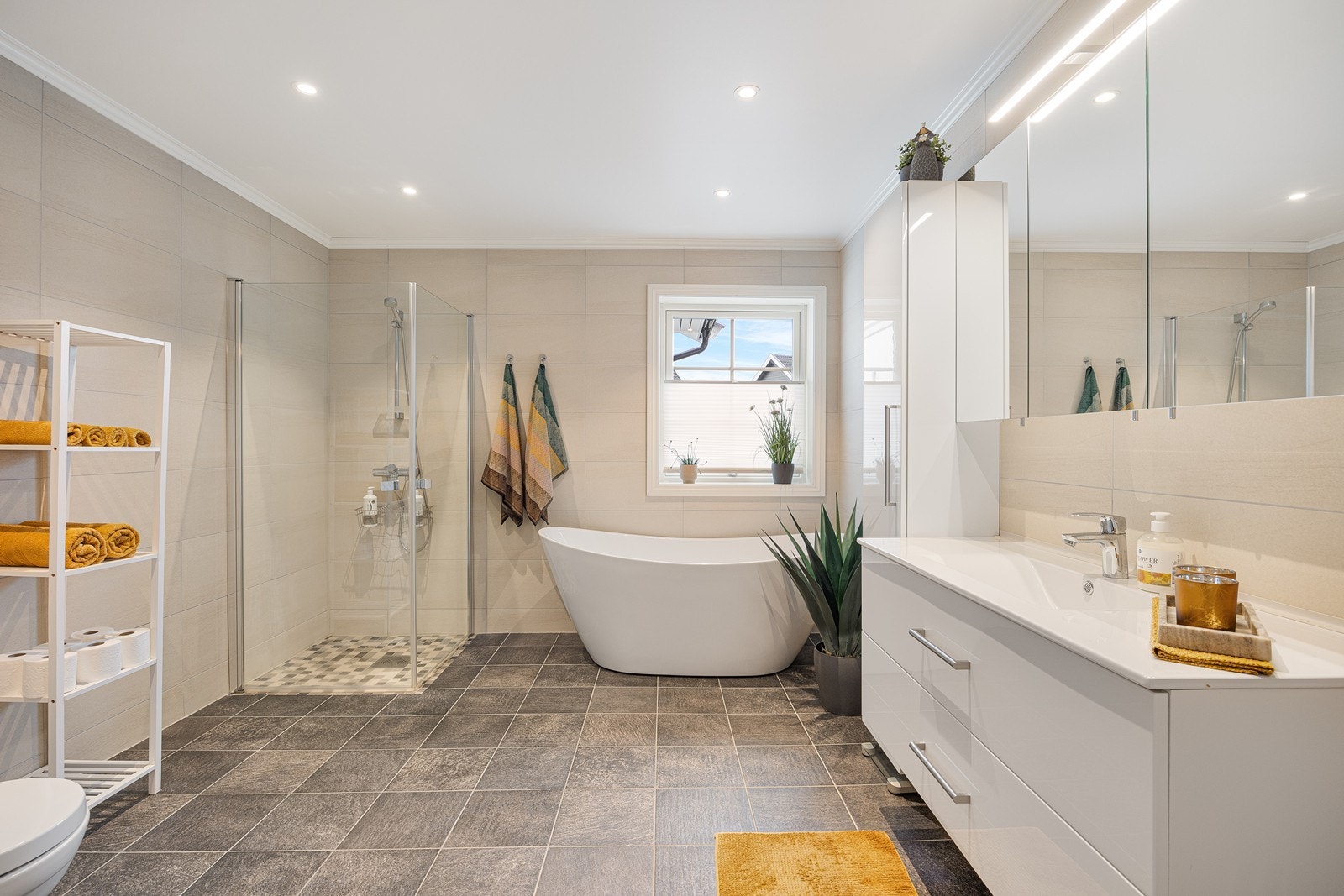 Badet har videre dusjnisje med rette glassdører, vegghengt toalett og speil over en skuffeseksjon med heldekkende servant. Galleribilde