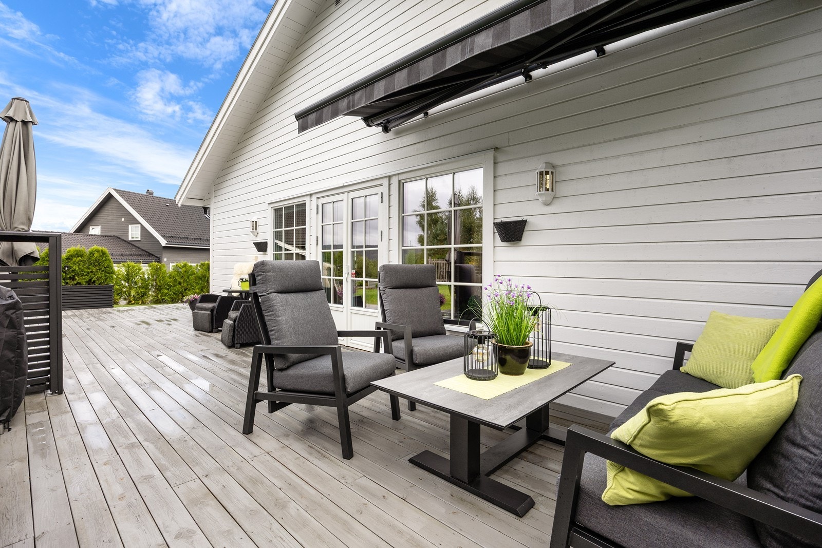 Markterrassen er skjermet av to store plantekasser med vintergrønne thujaer i det ene hjørnet og en vinklet spilevegg ved ved terrassedøren. Galleribilde