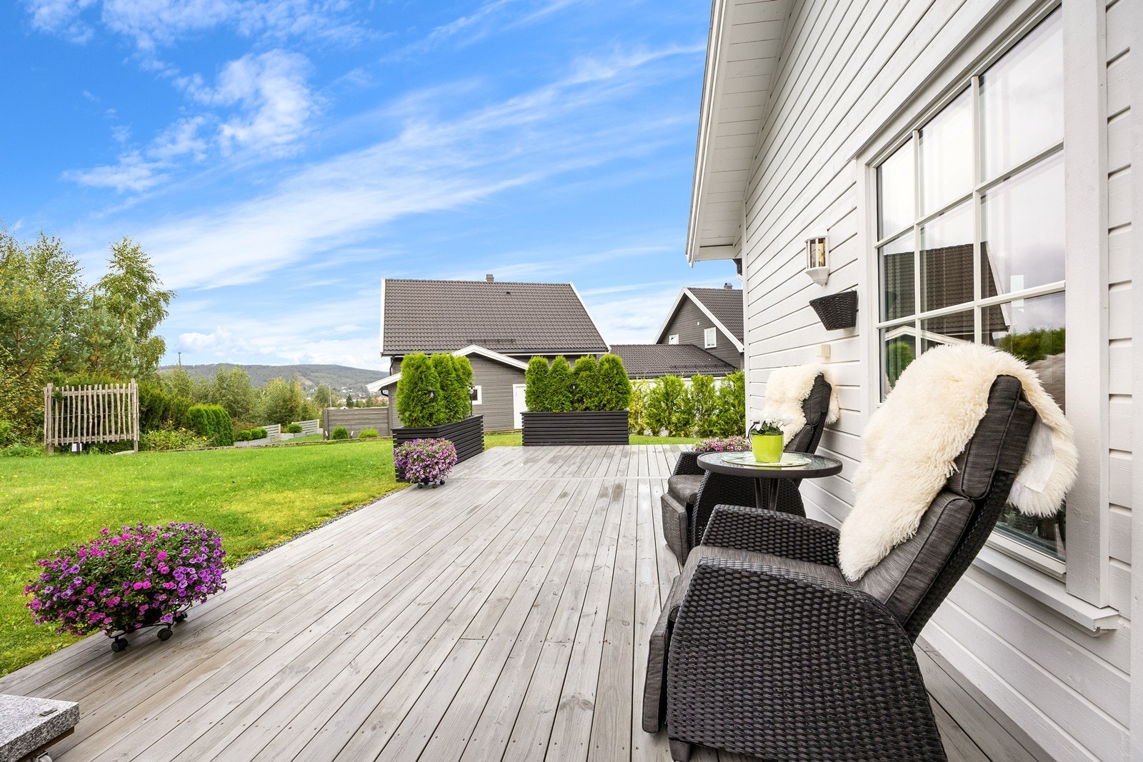 Den solrike tomten er opparbeidet med plen, vintergrønn hekk og en oppbarket skråning. Galleribilde