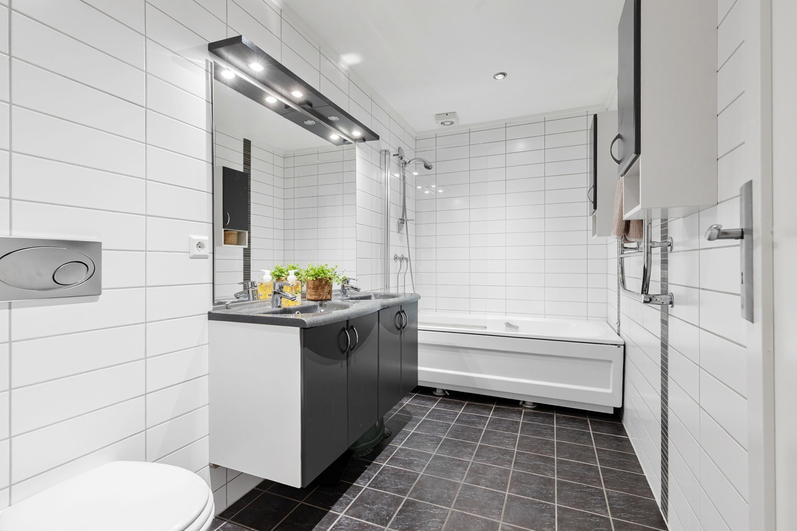 Romslig, flislagt baderom med varmekabler i gulvet og downlightsbelysning i taket. Galleribilde