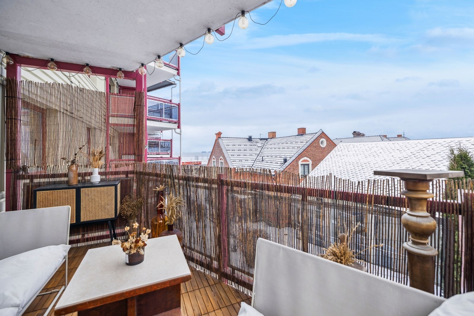 Uteplassen har takoverbygg fra balkongen i etasjen over og gulv med treheller. Mjøsutsikt fra ytre del av balkong. Galleribilde