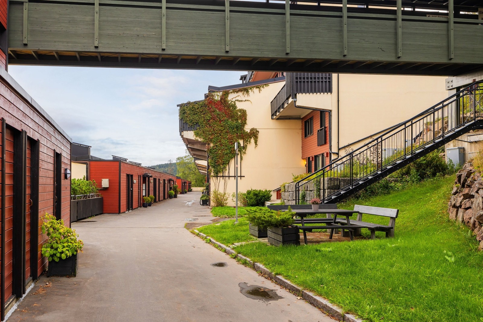Inngangspartiet på bakkeplan på baksiden, boddører ses på siden bortover. Boden til leiligheten er den siste på venstre side her. Bildet er tatt mot nord.
Gangbru øverst i bildet fra 8.plan =15.etasje inn til heisen. Galleribilde