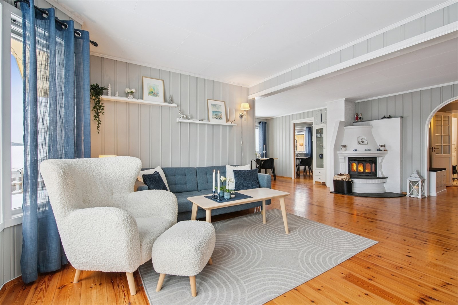 Romslig stue med god plass for flere sittegrupper og panel på veggene. Galleribilde