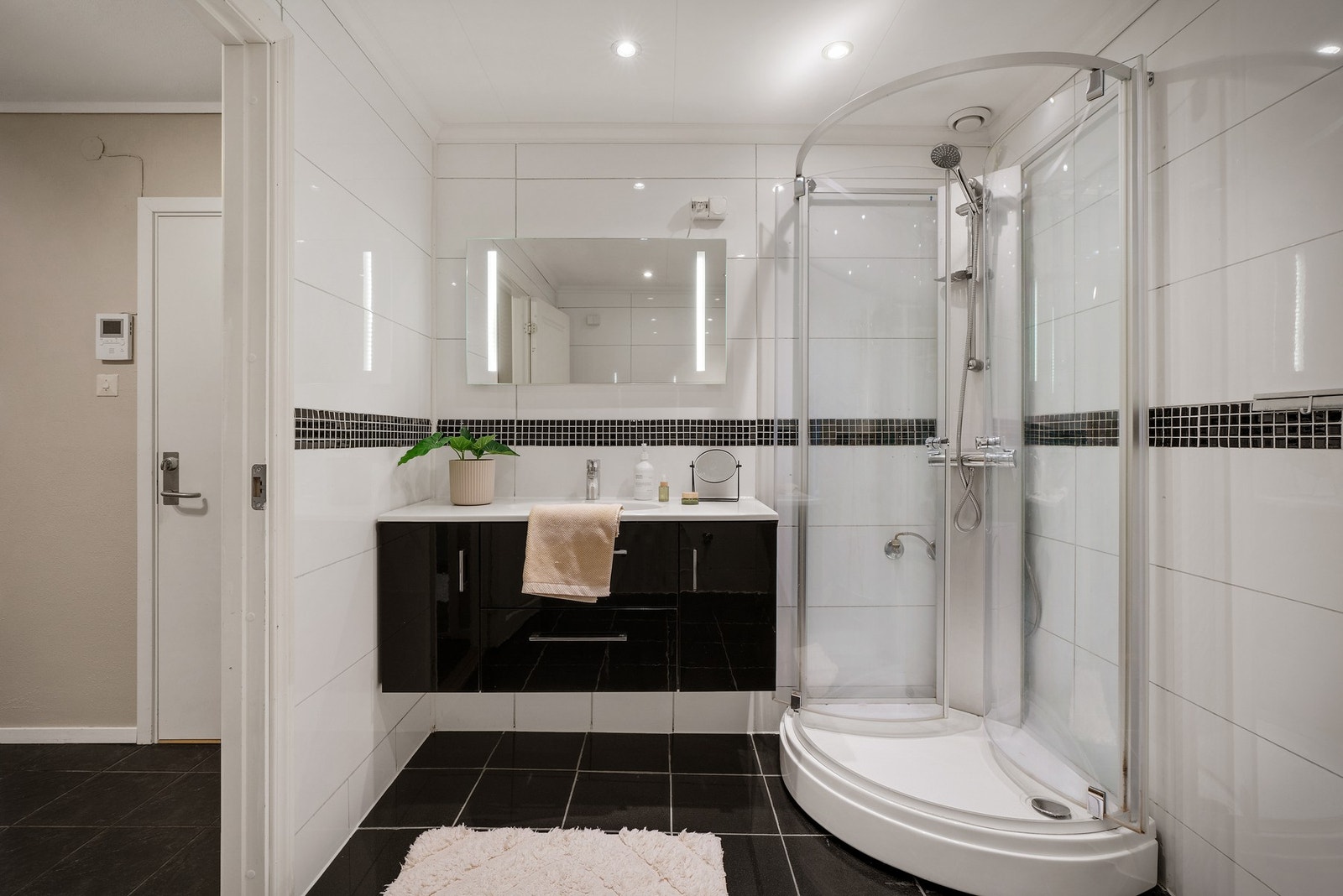 Badet inneholder helstøpt servant, skap og skuffer under servant med slette fronter og dusjkabinett. Galleribilde