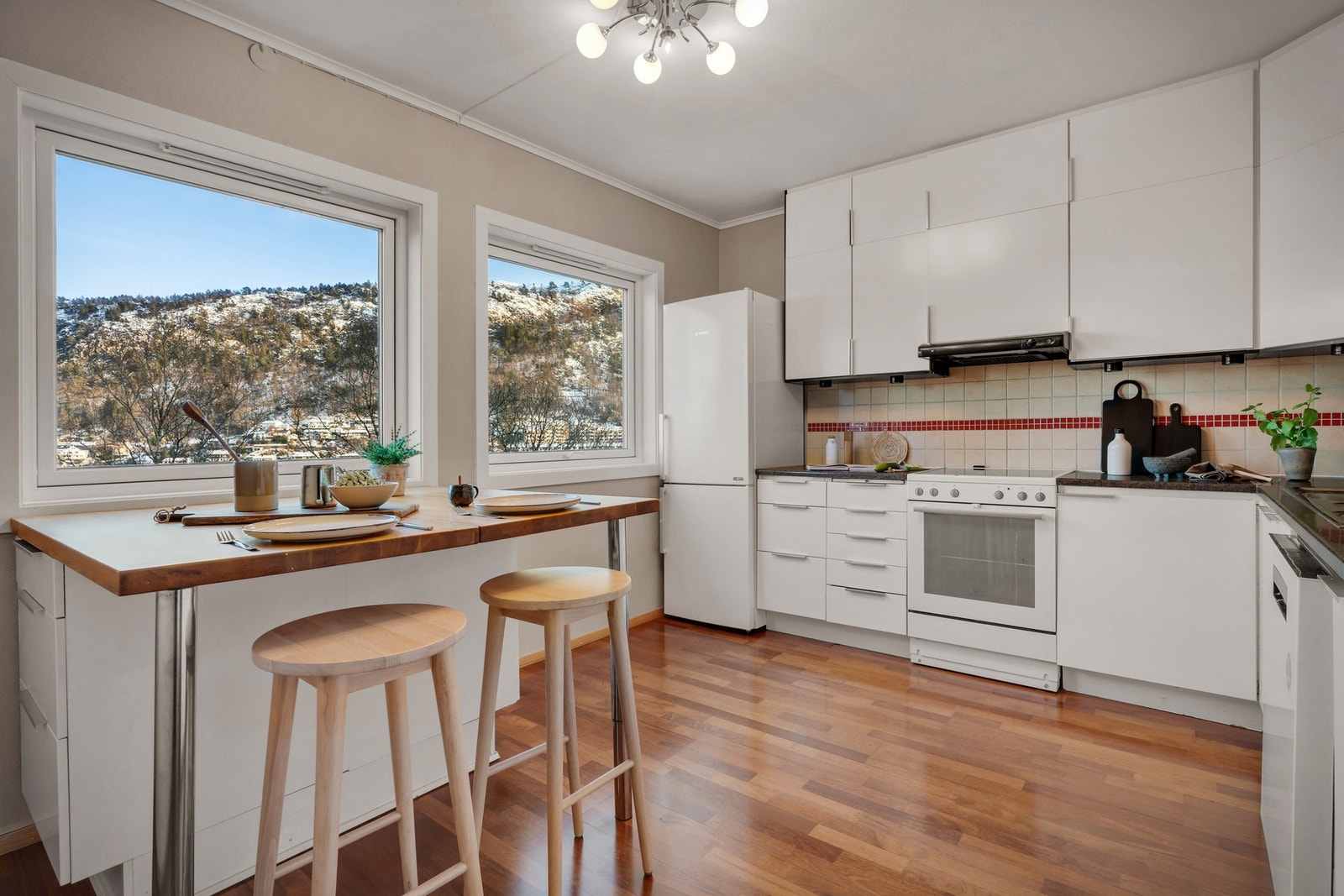 Kjøkkeninnredning med slette fronter, ett av overskapene har glassfront, laminat og heltre benkeplate. Galleribilde